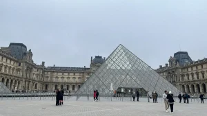 ルーヴル美術館のガラスのピラミッド前に立つ旅行者たち