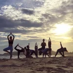 バイロンベイのビーチでサンセットを背景にヨガ