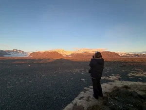 夕暮れのアイスランドの大地と山並みを眺める旅行者