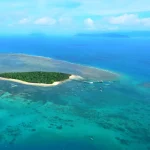 ケアンズ沖のグレートバリアリーフに浮かぶ小島とサンゴ礁の海を上空から撮影した風景