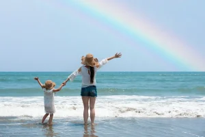 虹のかかるビーチでオーダーメイド旅行を楽しむ子連れ家族