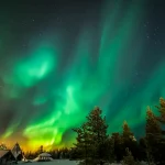 雪景色の森の上に広がるフィンランドのオーロラ