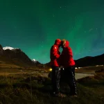 オーロラが広がる夜空の下で寄り添うハネムーン中のカップル