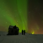 雪原でふたりがオーロラを眺めるハネムーン向けの夜景