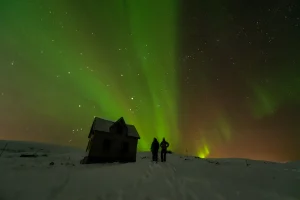 雪原でふたりがオーロラを眺めるハネムーン向けの夜景