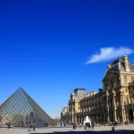 青空の下に広がるパリのルーヴル美術館とガラスのピラミッドの風景