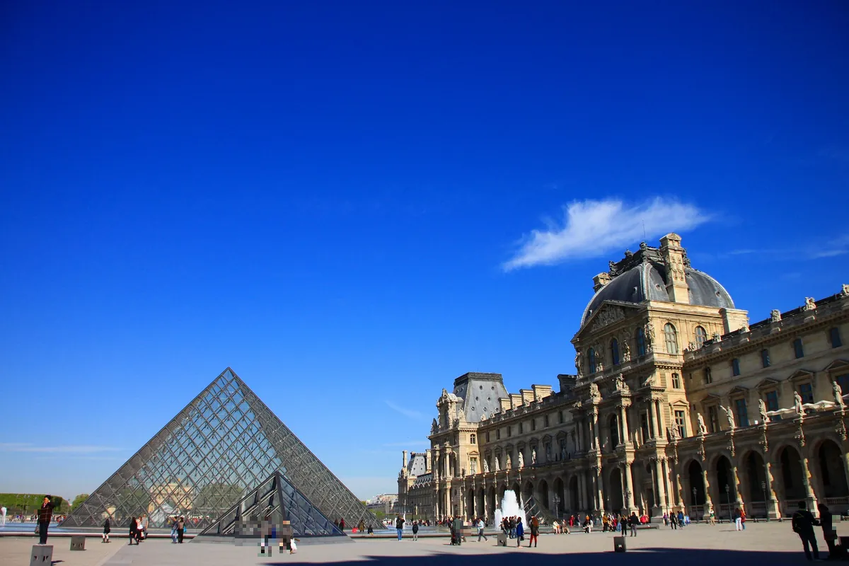 青空の下に広がるパリのルーヴル美術館とガラスのピラミッドの風景
