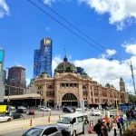 青空の下に建つメルボルンのフリンダース・ストリート駅と市街地の風景