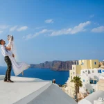 ヨーロッパ新婚旅行記事のサントリーニの青い海と白い街並みを背景にした新婚旅行のカップル