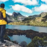タスマニアの山と湖を望む展望地で、旅行者が雄大な自然風景を眺めている様子