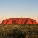 ウルル（エアーズロック）を中央に望むオーストラリア内陸部の赤い大地と草原風景