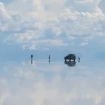 ウユニ塩湖の鏡張りに空と雲が映り込む幻想的な絶景と旅行者の姿