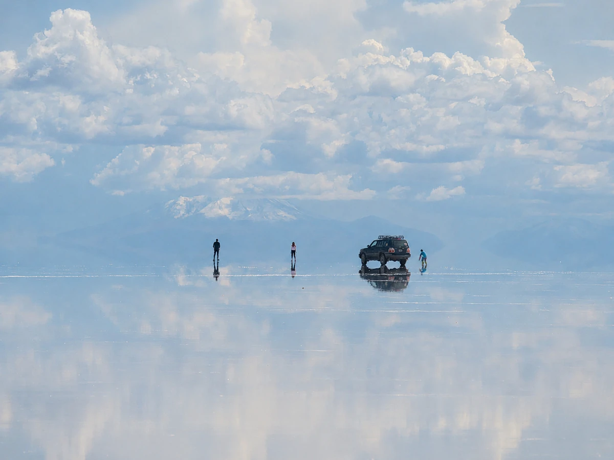 ウユニ塩湖の鏡張りに空と雲が映り込む幻想的な絶景と旅行者の姿