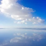 ウユニ塩湖の水面に青空と雲が映り込む雨季の鏡張り風景