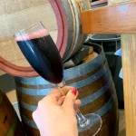 オーストラリアのワイナリーで赤ワインを試飲する手元と木樽の風景