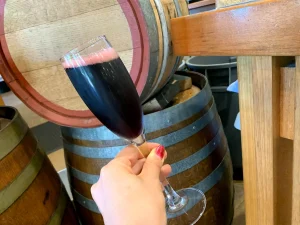 オーストラリアのワイナリーで赤ワインを試飲する手元と木樽の風景