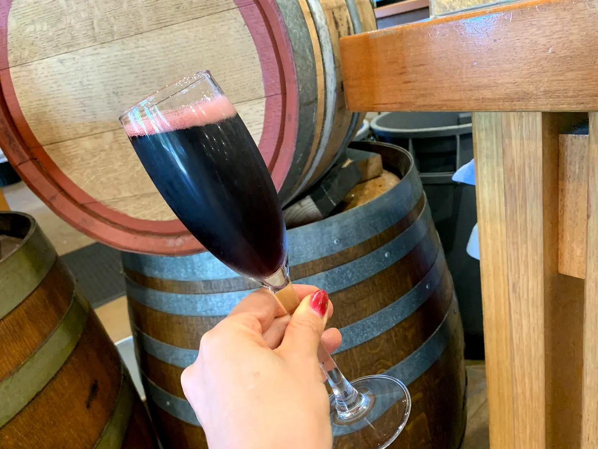 オーストラリアのワイナリーで赤ワインを試飲する手元と木樽の風景