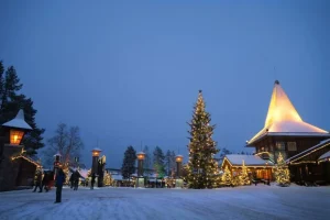 雪に包まれたフィンランドの村でクリスマスツリーと建物がライトアップされた風景