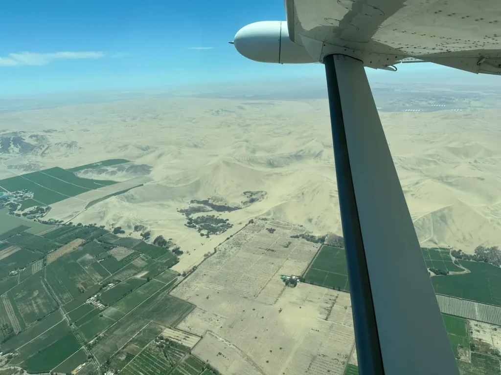 ナスカ上空を飛ぶ小型機から見た、砂漠と農地が広がるペルー南部の景色