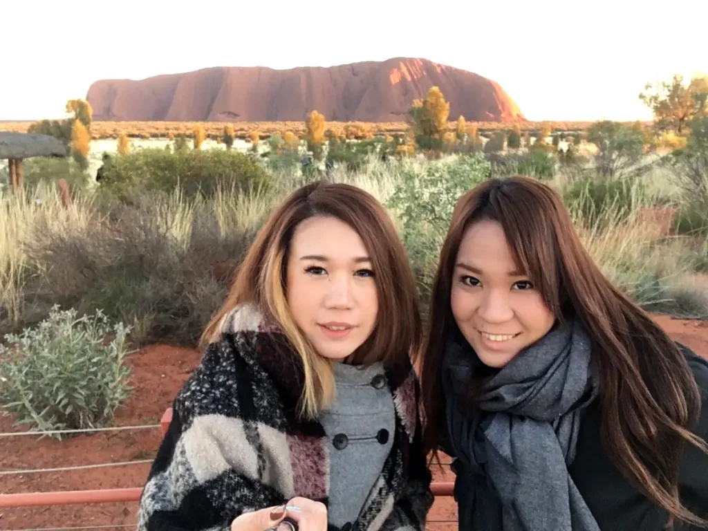 夕暮れのウルルを背景に記念撮影を楽しむオーストラリア女子旅の様子