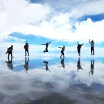 ウユニ塩湖の鏡張りでジャンプする旅行者と青空が映り込むトリック写真