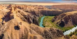 カザフスタンのチャリンキャニオンを流れる川と赤褐色の大峡谷を望むパノラマ風景