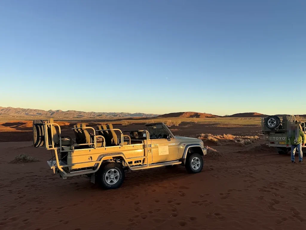 ナミビアの砂漠地帯に停車するオープンタイプの4WDサファリ車