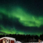 雪景色の夜空に広がるオーロラ。一人旅でも、送迎付きツアーを選べば安心して観賞を楽しみやすいです。