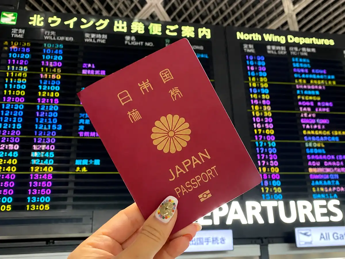 空港の出発案内板と日本のパスポート