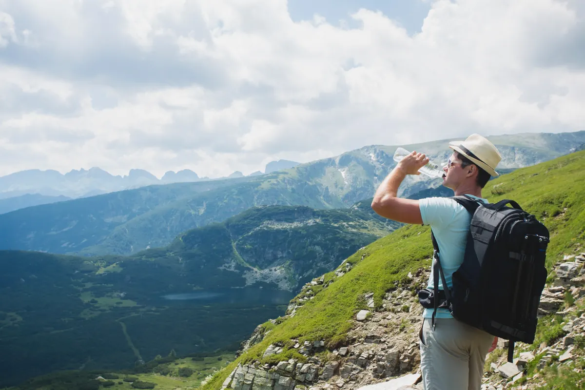 山道で水分補給する登山者