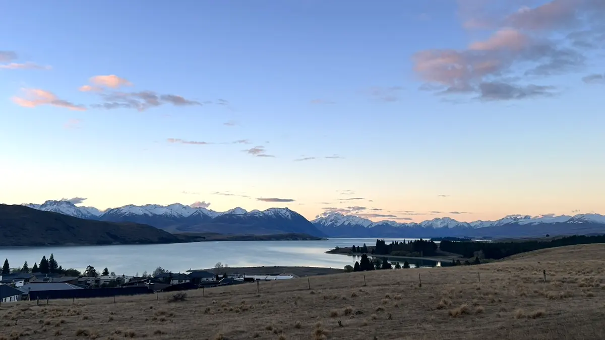 夕暮れのテカポ湖と湖畔の建物、雪を頂く山並み